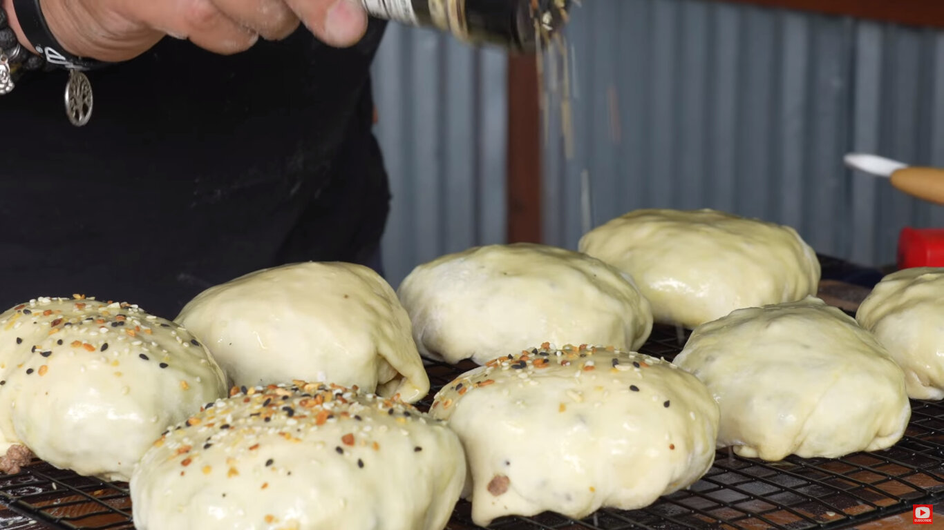 topping being sprinkled onto bacon burger bombs